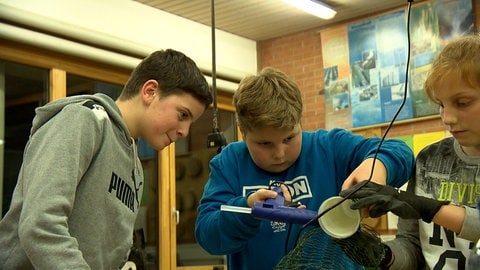 Drei Jungen im Werkraum mit einer Laterne