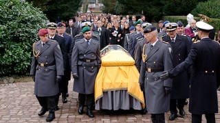 Neben dem Sarg stehen viele Soldatinnen und Soldaten in Uniform. Sie befinden sich bereits auf dem Friedhof von Offenburg.
