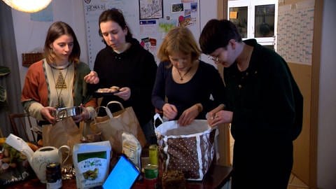 Menschen stehen an Tisch und essen 