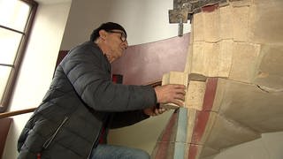 Mann restauriert historische Wendeltreppe