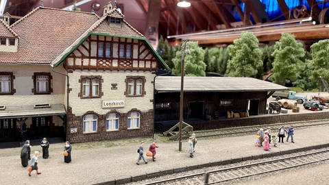 Blick auf einen Modellbahnhof mit kleinen Menschenfiguren.