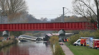 Ein Zug in einem Kanal, zerbrochen, Rettungswagen stehen vor den Brückenpfeilern