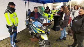 Ein Menschen mit Behinderung sitzt auf einem Polizeimotorrad.