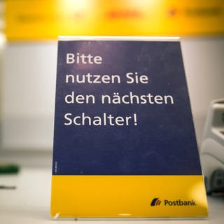 Auf dem Land sind Postfilialen knapp - Postschalter mit Schild: Bitte nutzen Sie den nächsten Schalter