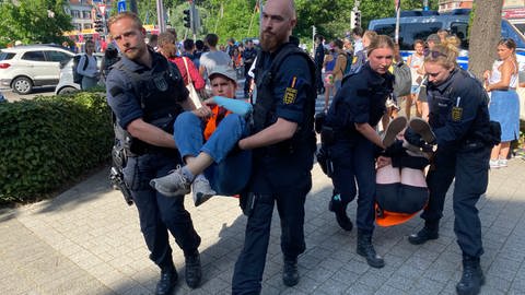 Polizistinnen und Polizisten tragen Mitglieder der "Letzten Generation" nach einer Sitzblockade im Freiburger Stadtteil Wiehre weg. 