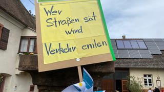 Auf einem Protestschild gegen den Ausbau der B31a-West steht: "Wer Straßen säht, wird Verkehr ernten."