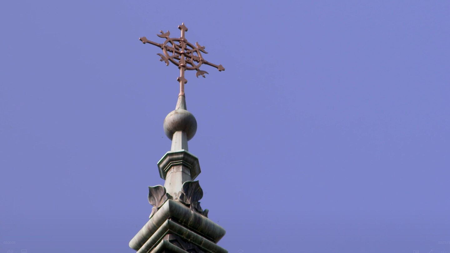 Ein Kreuz auf dem Dach einer katholischen Kirche.