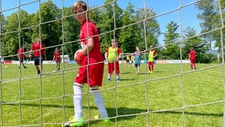 Junge steht im Tor und dreht sich nach hinten zur Kamera