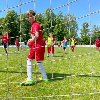 Junge steht im Tor und dreht sich nach hinten zur Kamera