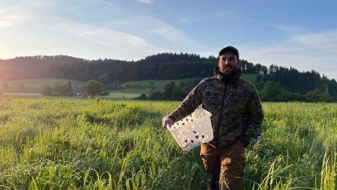 Mann läuft mit Wäschekorb über die Wiese