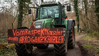 Am Rande des Besuchs von Bundeskanzler Scholz demonstrieren Landwirte aus der Region gegen die aktuelle Bundesregierung. Auf einem Schild eines Traktors steht "Vom Respekt-Kanzler zum Arroganz-Kanzler" geschrieben.