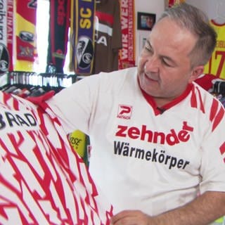 Mann schaut sich ein Fußballtrikot an