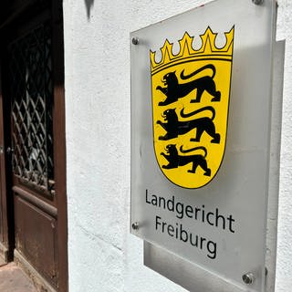 Neben der Tür des Freiburger Landgerichts hängt ein Schild mit dem Wappen des Bundeslandes.