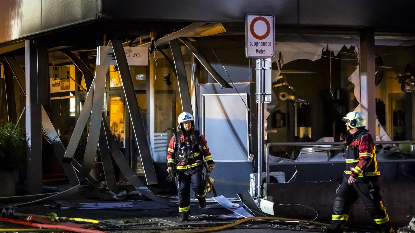 Zwei Feuerwehrmänner vor dem Hochhauskomplex im Schweizer Nussbaumen, wo es durch Feuerwerk zu mehreren Explosionen in einer Tiefgarage gekommen ist.