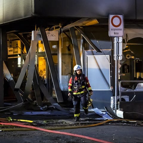 Zwei Feuerwehrmänner vor dem Hochhauskomplex im Schweizer Nussbaumen, wo es durch Feuerwerk zu mehreren Explosionen in einer Tiefgarage gekommen ist. 