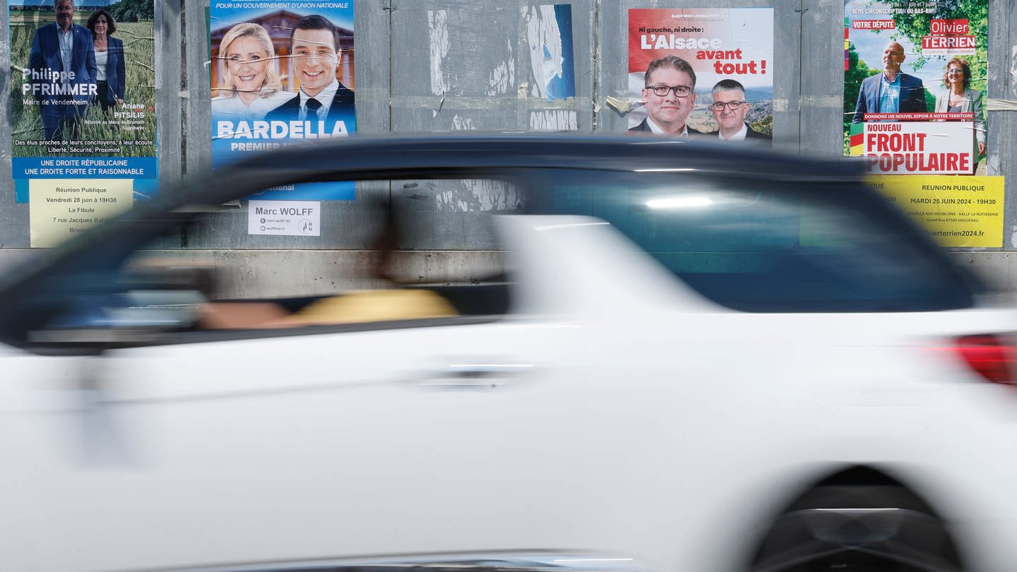 Ein Auto fährt an Wahlplakaten zur Parlamentswahl in Frankreich vorbei
