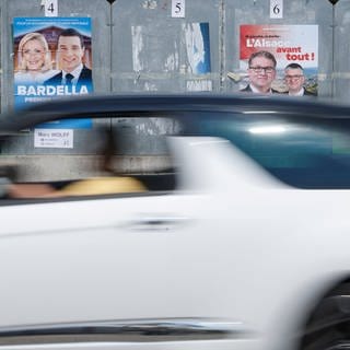 Ein Auto fährt an Wahlplakaten zur Parlamentswahl in Frankreich vorbei