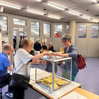 Eine Frau wirft ihren Wahlzettel für die Stichwahl der französischen Parlamentswahl in die Urne.