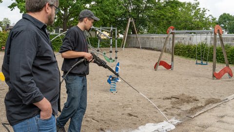 Zwei Männer verteilen ein Gemisch aus heißem Wasser und Schaum in Kehl. Damit versuchen sie, die Ameisen zu bekämpfen.