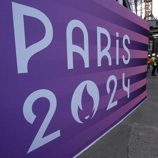 Ein großer Banner ist in Paris aufgestellt. Der Schriftzug: "Paris 2024". 