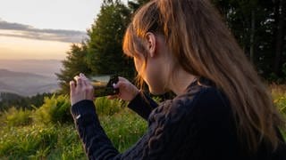 Eine Frau macht ein Foto von einem Sonnenuntergang.