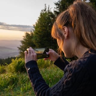 Eine Frau macht ein Foto von einem Sonnenuntergang.