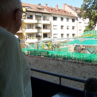 Ein Mann schaut von seinem Balkon auf einen abgetrennten Bereich, in dem Drogen konsumiert werden.