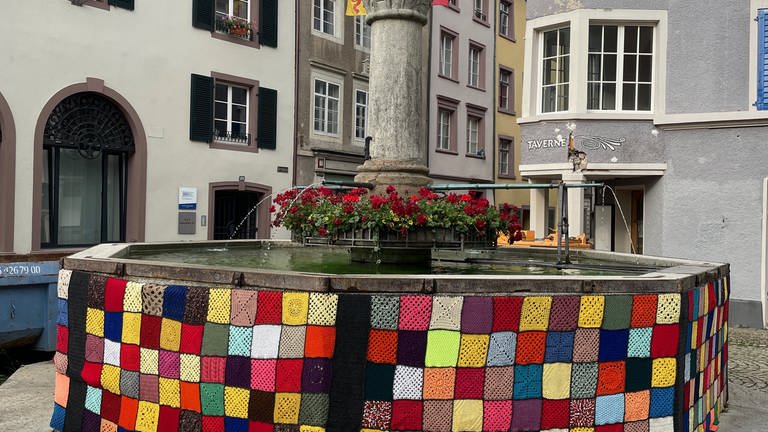 Auch der Brunnen wurde umhüllt von einem fleckenteppichartigem Mantel. Das bringt Farbe in die Stadt.