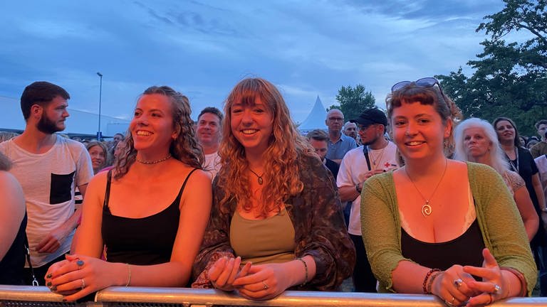 Drei junge Frauen stehen in der ersten Reihe des Open-Air-Konzertes von Sänger "Faber"