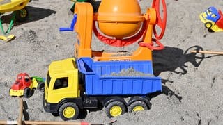 Kinderspielzeug für kleine Kinder, das in einem Sandkasten verteilt liegt. 