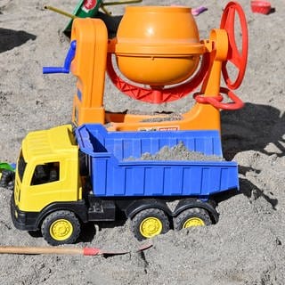 Kinderspielzeug für kleine Kinder, das in einem Sandkasten verteilt liegt. 