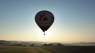 Ein Heißluftballon startet in den Sonnenaufgang