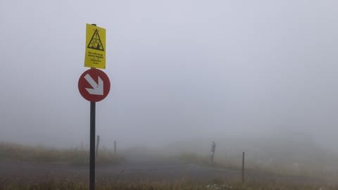 Ein Schild mit der Aufschrift "Hier endet das gesicherte Skigebiet" im dichten Nebel