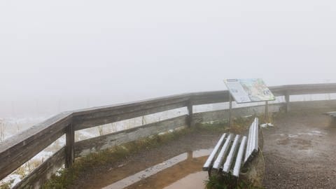 Schnee liegt auf einer Bank, die auf dem Feldberg-Gipfel steht. 