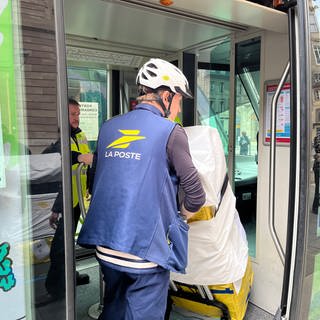 Postbote holt Pakete aus einer Straßenbahn in Straßburg.