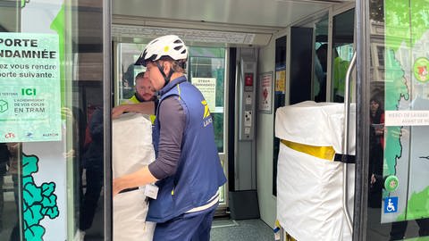 Postbote holt Pakete aus einer Straßenbahn in Straßburg.