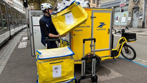 Postbote fährt mit einem Lastenrad Pakete aus in Straßburg.