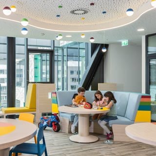 Drei Kinder spielen und malen im neuen bunten Wartebereich der Kinder- und Jugendklinik