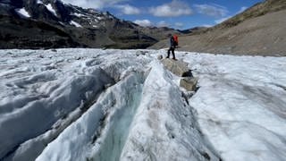 Immer weniger Gletscher in den Alpen: Ein Wanderer läuft über eine Gletscherfläche, dahinter ist viel Geröll.