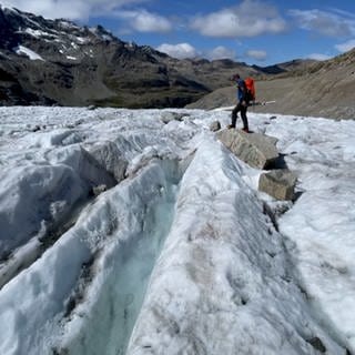 Immer weniger Gletscher in den Alpen: Ein Wanderer läuft über eine Gletscherfläche, dahinter ist viel Geröll.