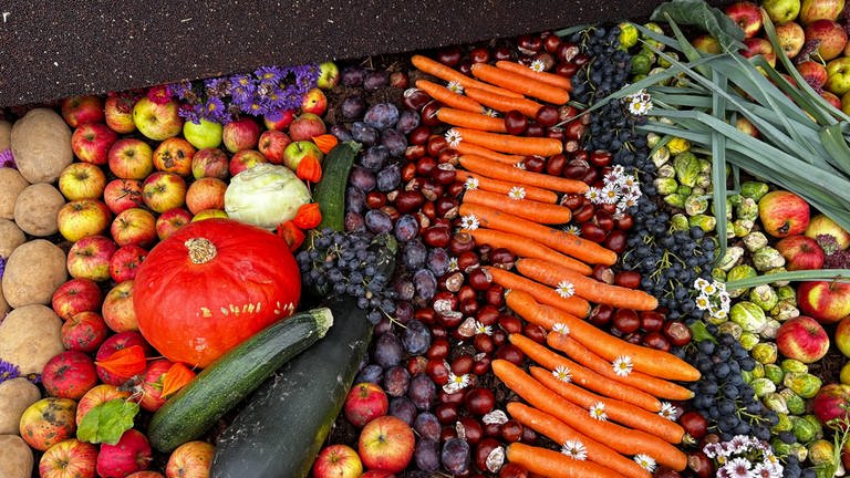 Für das Erntedankfest angerichtet: Frisch geerntetes Obst und Gemüse liegt vollkommen querbeet auf einem Wagen aus.