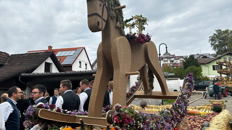 Ein circa 2 Meter großes Schaukelpferd aus (Kork?) steht auf einem Festwagen für den Erntedankfestumzug - natürlich mit reichlich Obst und Gemüse.