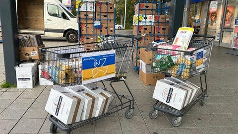 Vor einem Supermarkt stehen volle Einkaufswägen. Darin Spenden für die Menschen in der Ukraine. Darunter Windeln und lange haltbare Lebensmittel wie Mehl und Zucker.