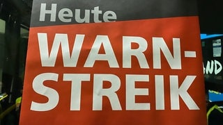 "Heute Warnstreik" steht auf einem Plakat der Gewerkschaft ver.di, das am Dienstag (15.10.) an der Scheibe eines Busses in Weil am Rhein (Kreis Lörrach) klebt.