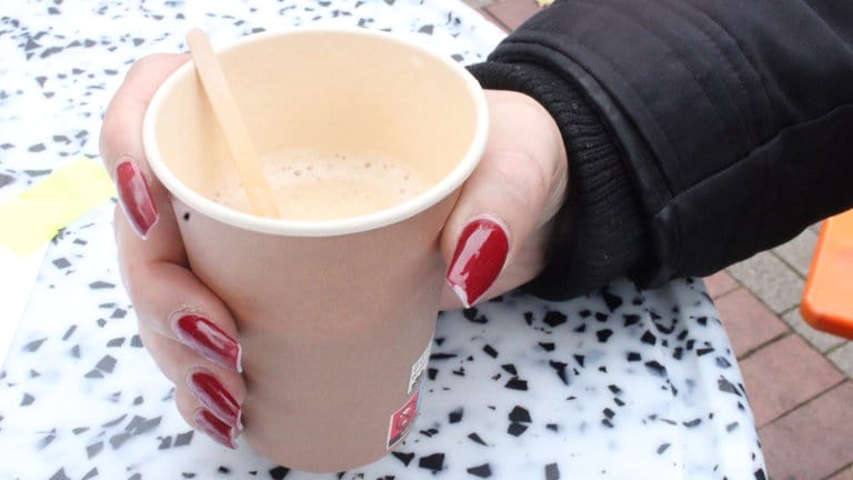 Eine Besucherin hält einen Pappbecher mit Hanfkaffe in der Hand: "Er schmeckt wie normaler Kaffee, nur etwas süßer. Sehr lecker!"