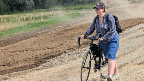 Frau mit Brille und mittellangen Haaren trägt eine Bluse.