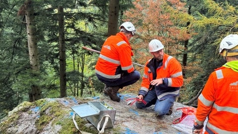 Drei Männer präparieren einen Fels im Höllental, um ihn kontrolliert zu sprengen. 