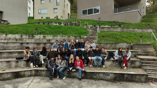 Schülerinnen und Schüler sitzen auf Treppenstufen vor Gebäuden des United World College.