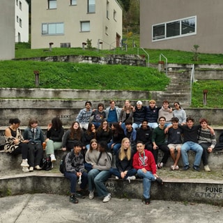 Schülerinnen und Schüler sitzen auf Treppenstufen vor Gebäuden des United World College.