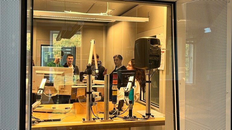 Die Praktikantinnen und Praktikanten stehen in einem Radiostudio.